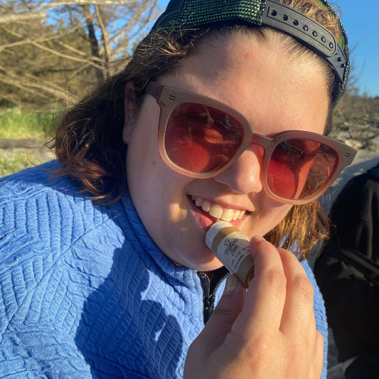 A cool person applying CBD lip balm outdoors