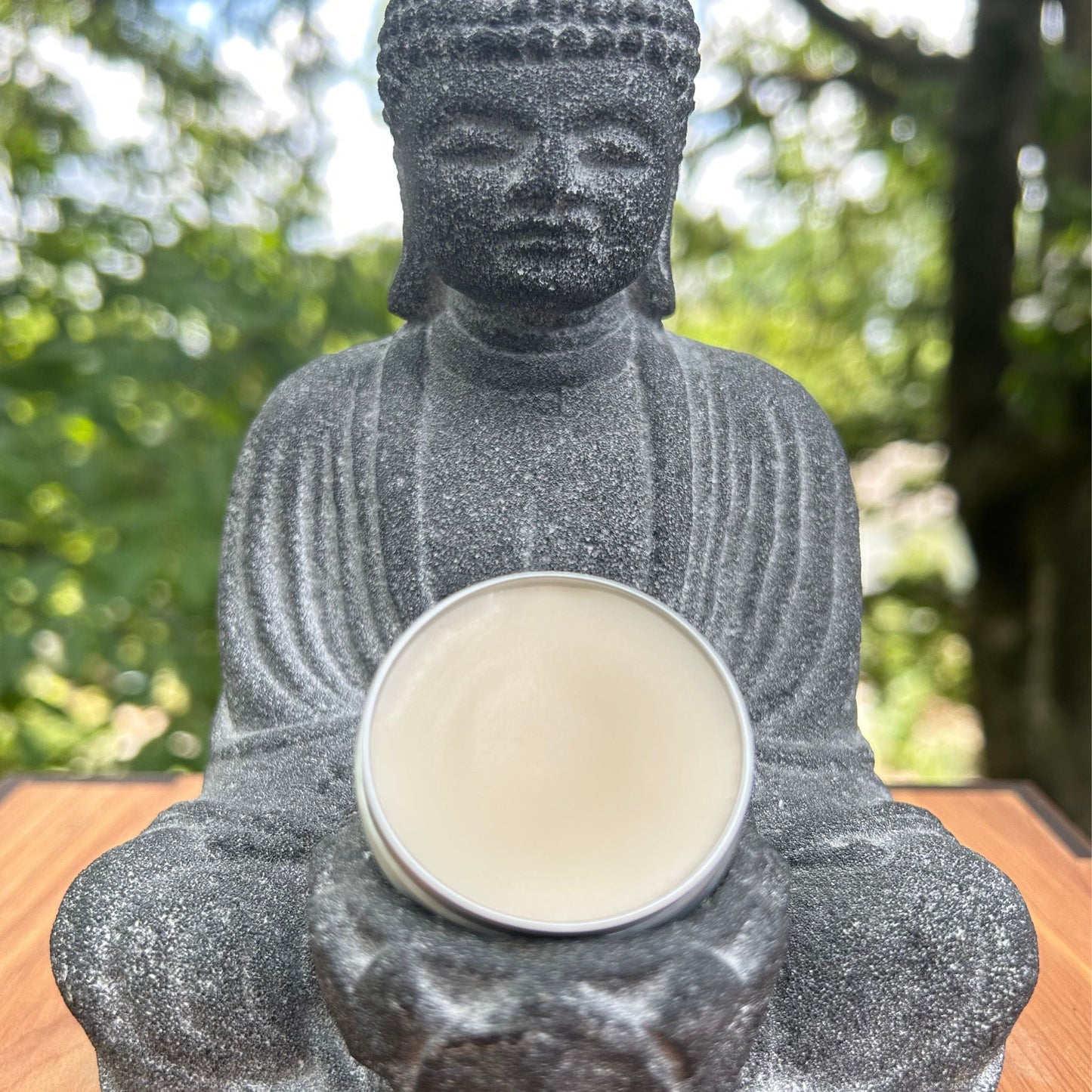Small tin of cbd muscle salve outdoors in buddha's lap