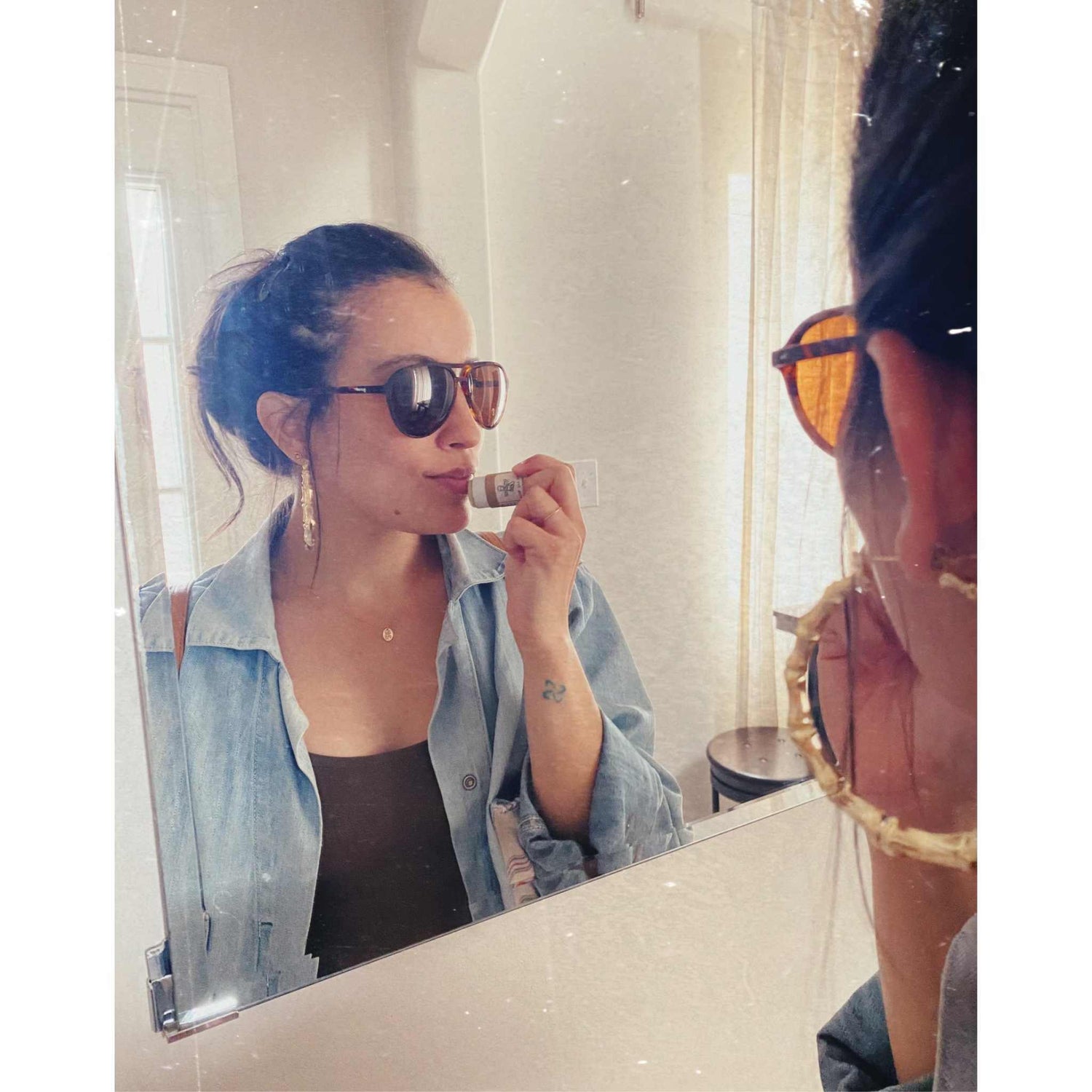 Attractive woman applying Mellow Oak lip balm in the mirror