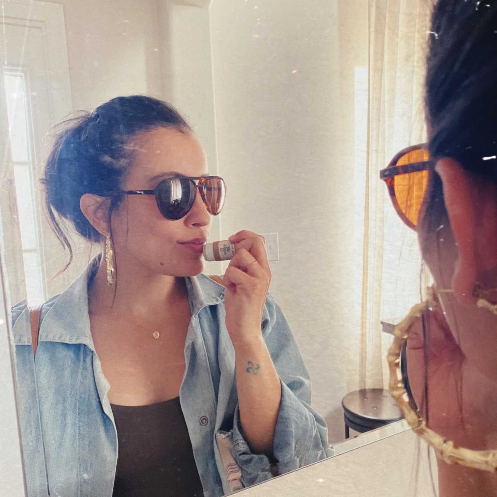 woman applying lip balm in the mirror