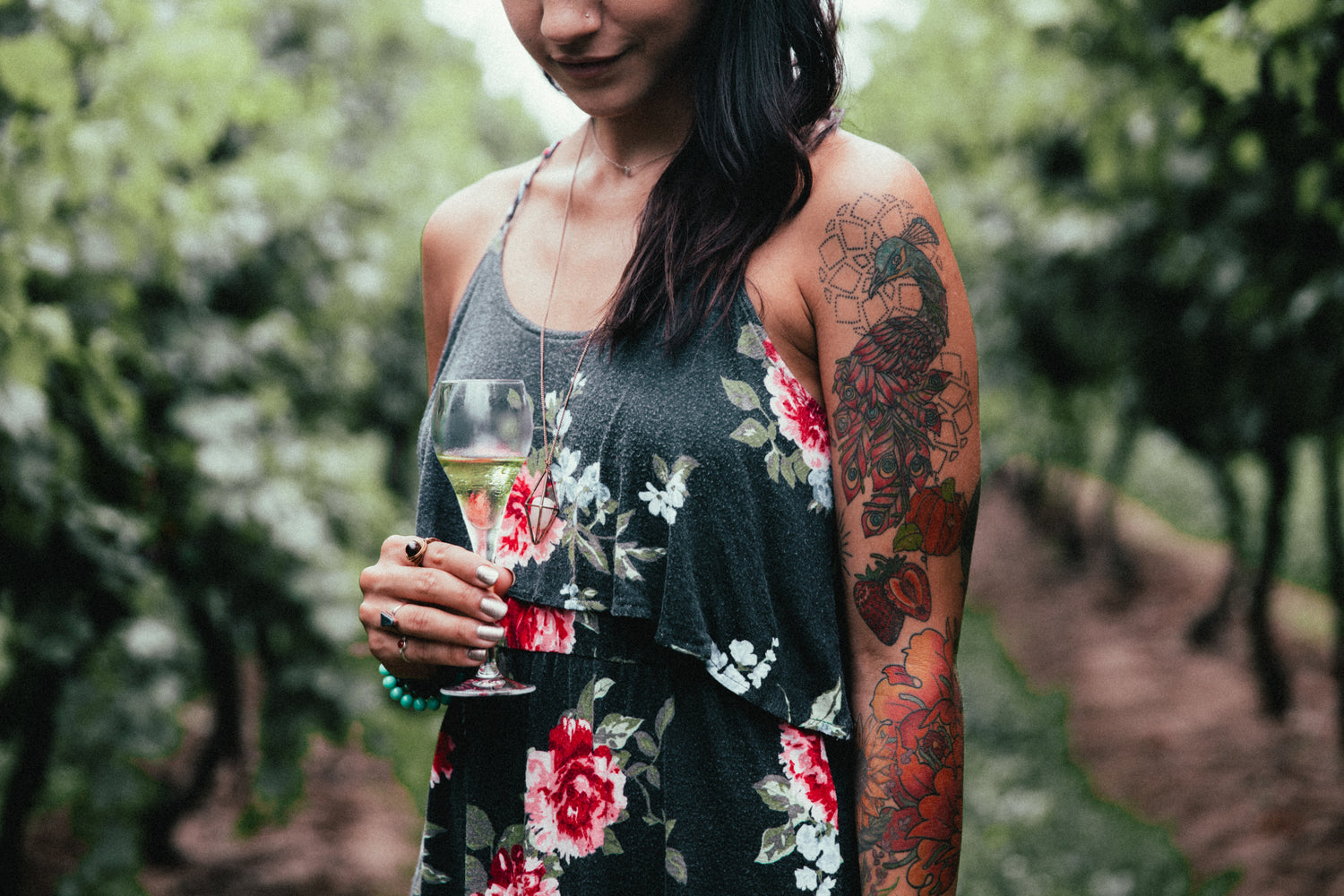 Woman with tattoos holding a glass of wine outdoors