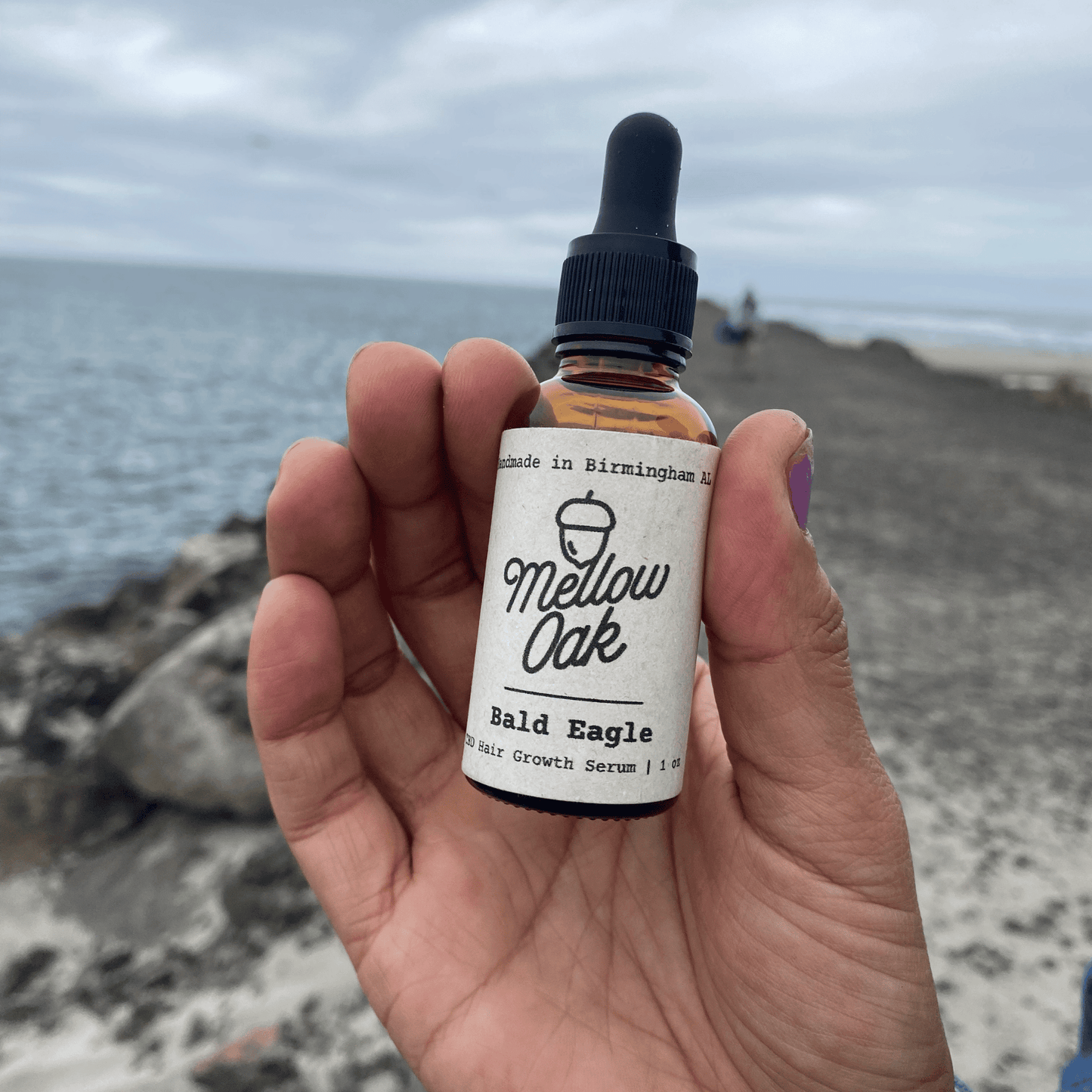 Woman holding Bald Eagle CBD Hair Growth Serum by the water