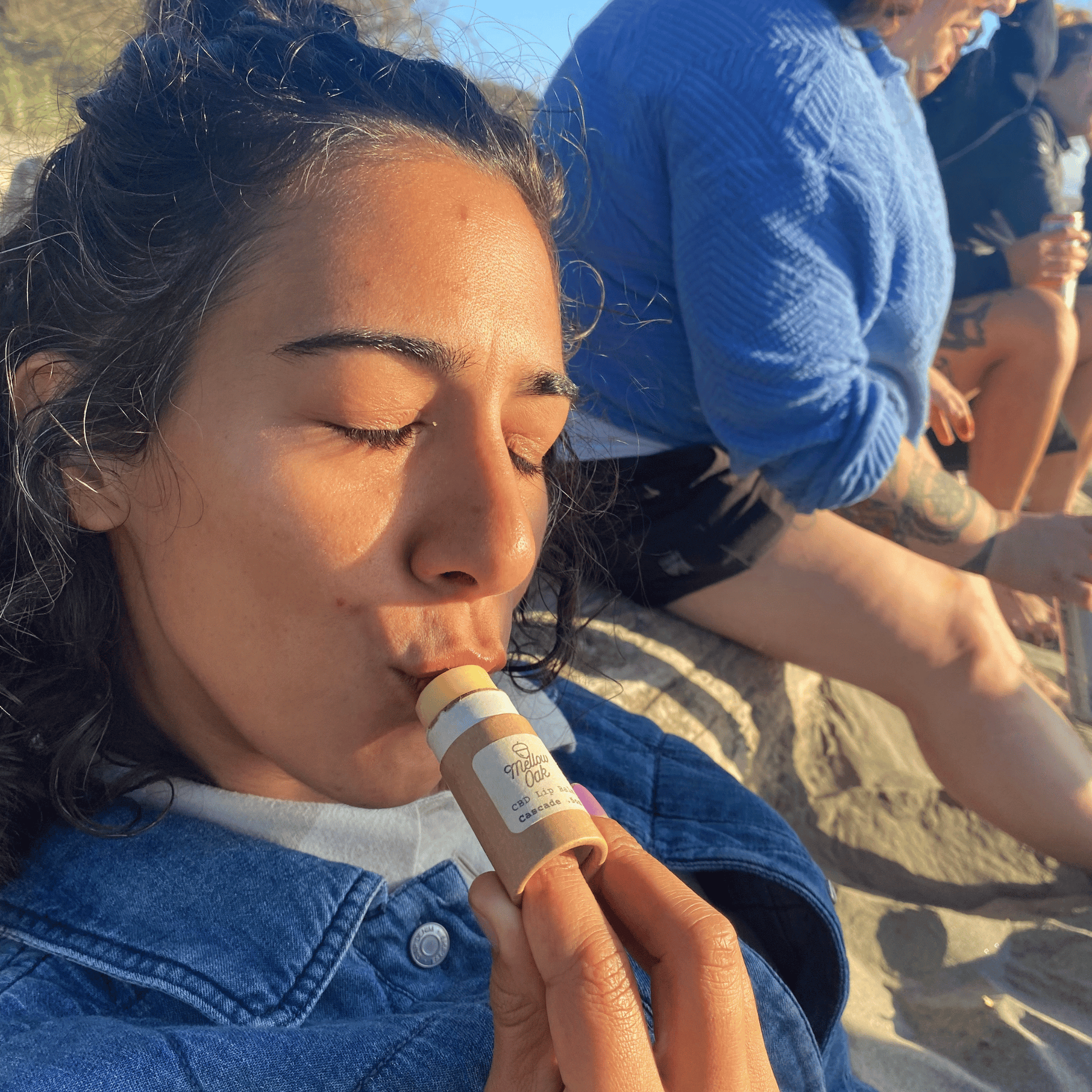Girl applying CBD lip balm made from organic unrefined shea butter in paper tubes outdoors