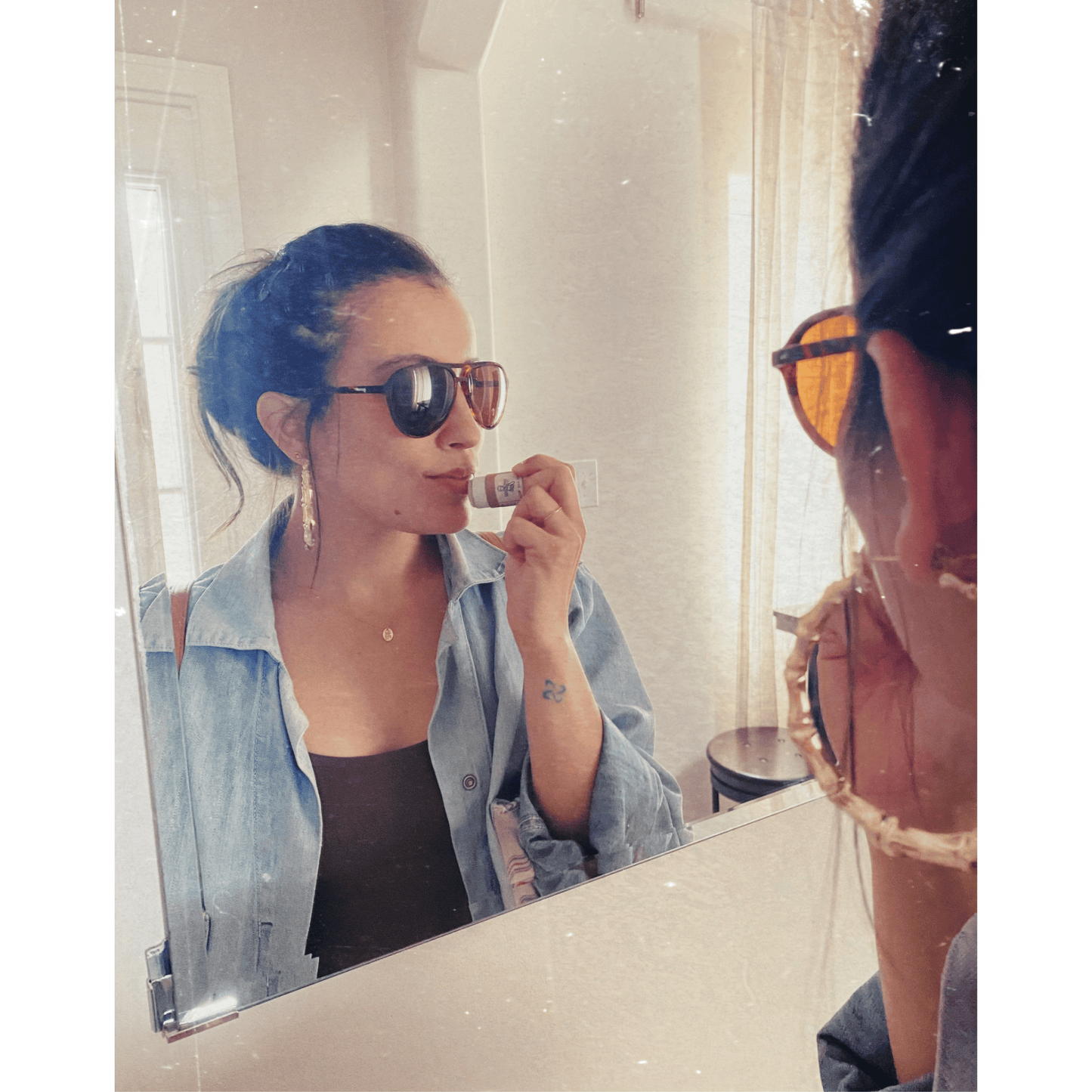Woman applying cbd lip balm in mirror